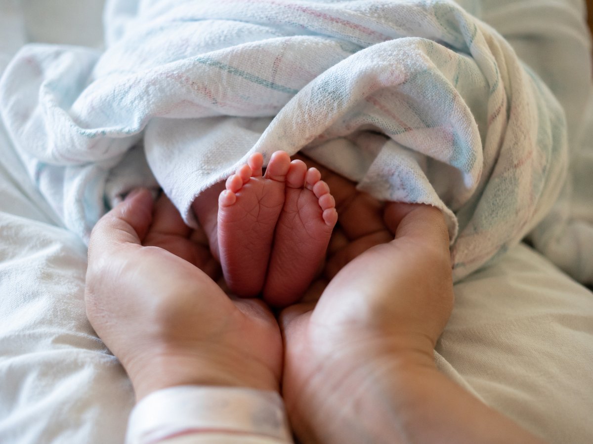 Gros plan sur les mains et pieds d'un nouveau-né à la maternité, lumière naturelle douce
