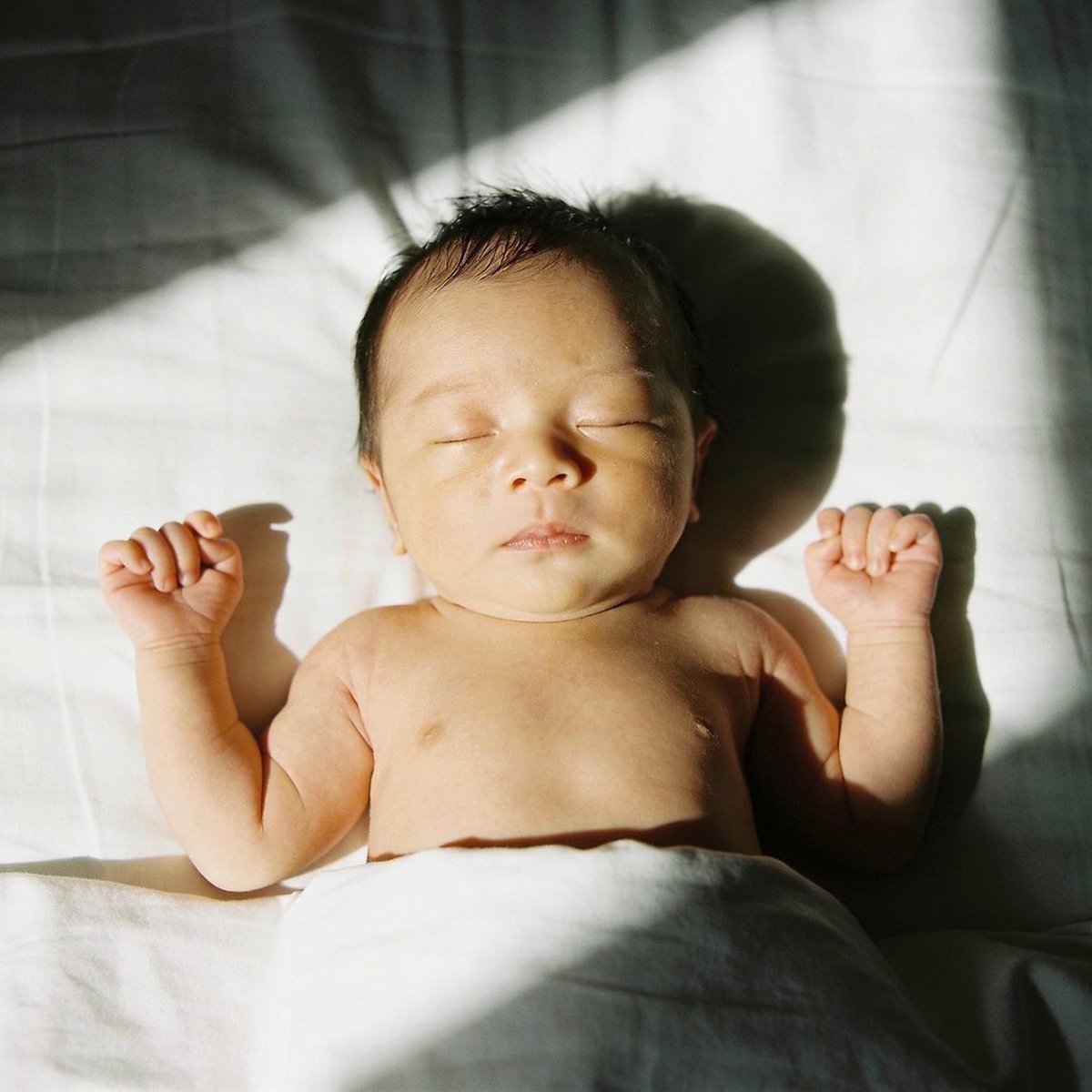 Bébé photographié avec lumière naturelle douce près d'une fenêtre à angle 45 degrés