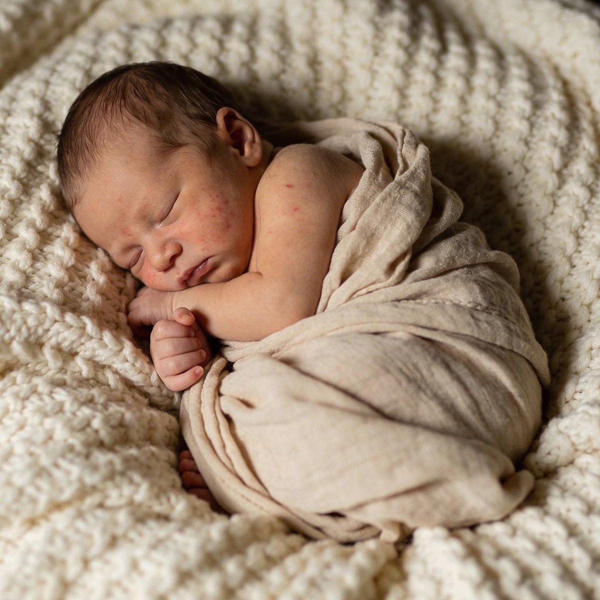 Bébé nouveau-né endormi dans une pose artistique lovée, photographié entre 5 et 15 jours
